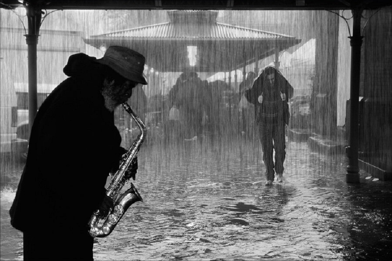 Одинокий саксофон. Человек под дождем. Идет под дождем. Человек в шляпе под дождем. Мужчина в шляпе под дождем.
